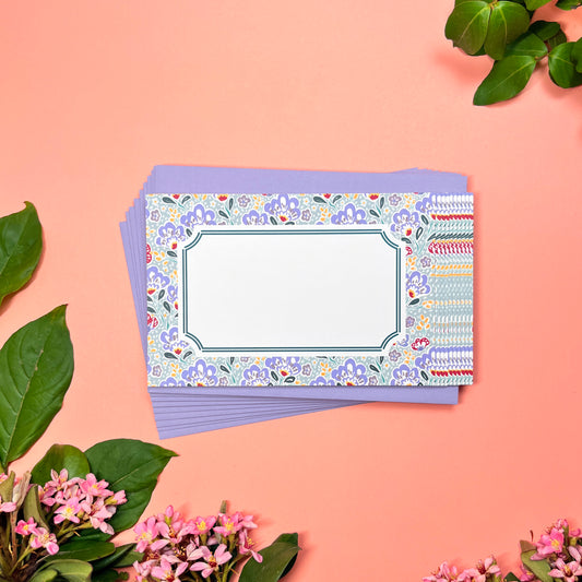 Mahjong inspired flat note set of 10 for greeting cards. Features silver blue paisley pattern with a bamboo hinted frame for a warm handwritten letter. Lilac periwinkle pebble pattern printed on back. Shown on a stack of 10 lilac envelopes.