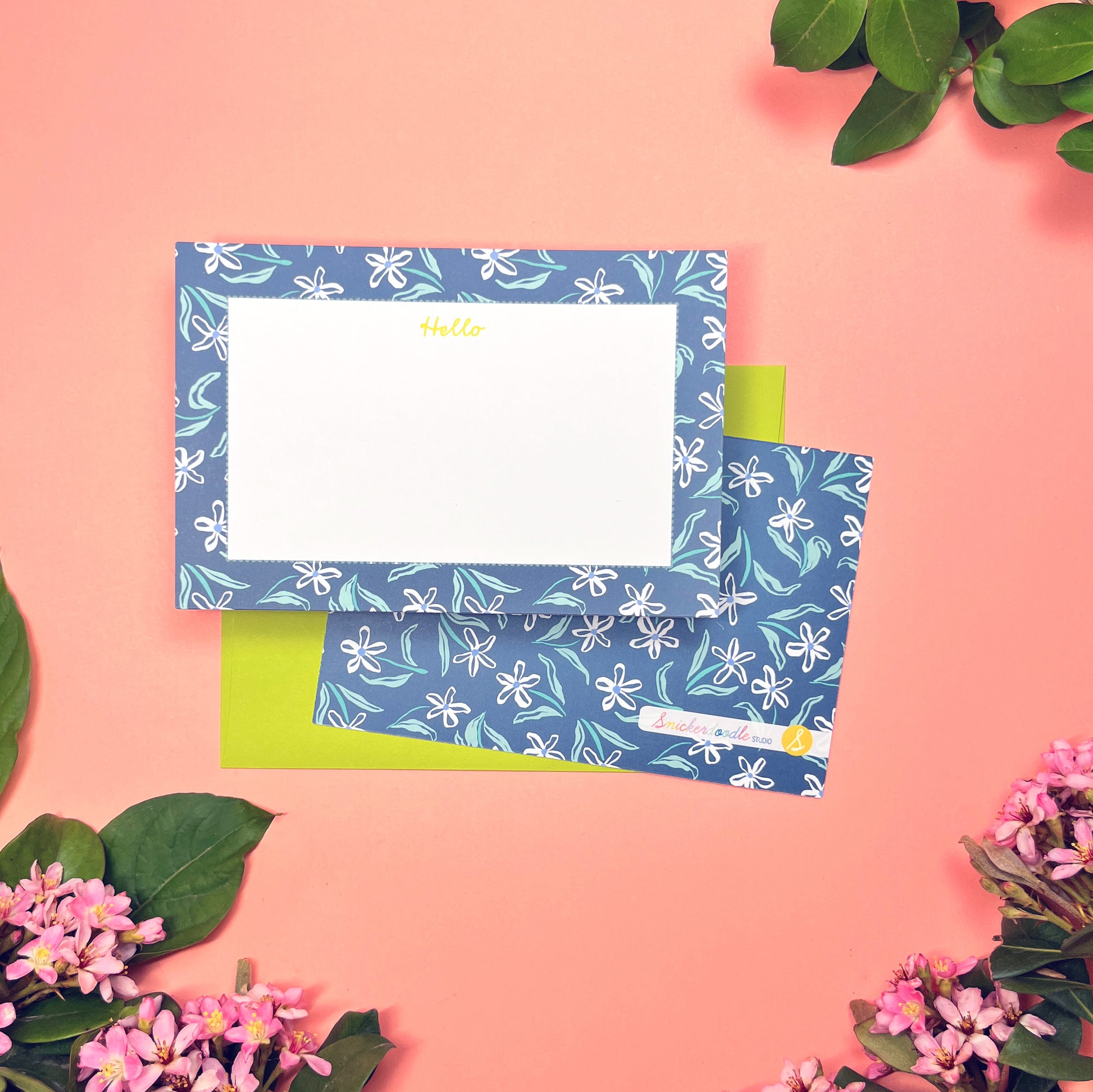 White dainty flower pattern on a blue background with teal and periwinkle accents. Stationery set of 10 with envelopes. Greeting says "Hello" in lime green. Shown with a lilac envelope.