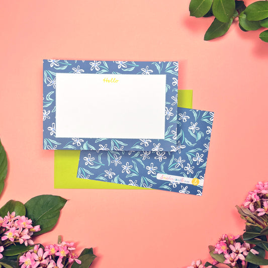 White dainty flower pattern on a blue background with teal and periwinkle accents. Stationery set of 10 with envelopes. Greeting says "Hello" in lime green. Shown with a lilac envelope.