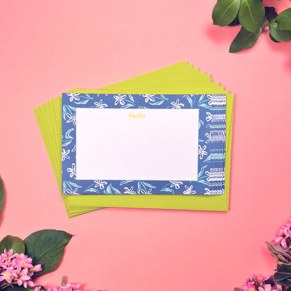 White dainty flower pattern on a blue background with teal and periwinkle accents. Stationery set of 10 with envelopes. Greeting says "Hello" in lime green. Shown with a stack of lime green envelope.