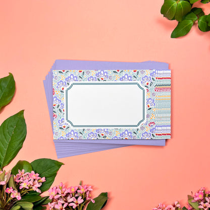 Mahjong inspired flat note set of 10 for greeting cards. Features silver blue paisley pattern with a bamboo hinted frame for a warm handwritten letter. Lilac periwinkle pebble pattern printed on back. Shown on a stack of 10 lilac envelopes.