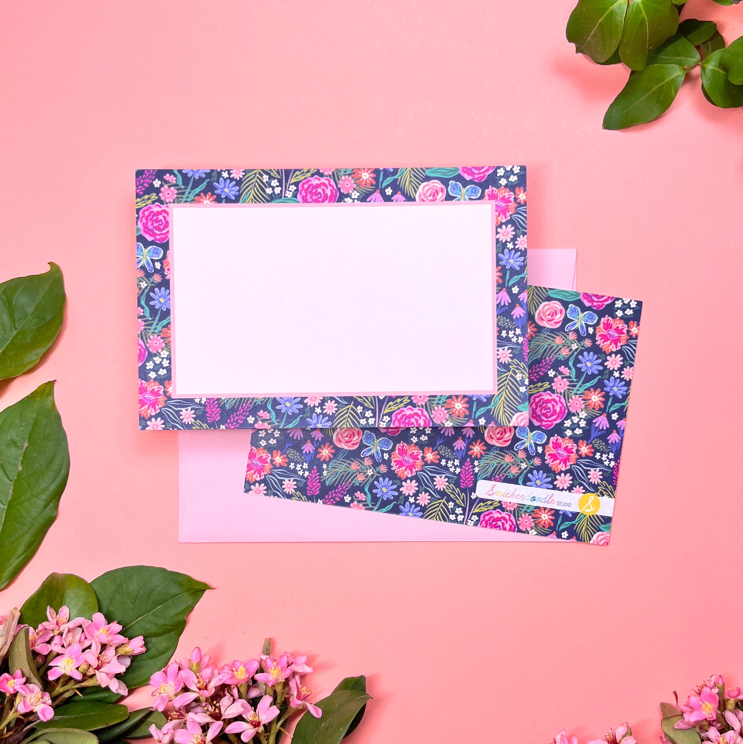The Summer Night Floral pattern shows beautifully calm, but bright florals on a deep navy background with a bright blue butterfly. This Stationery set of 10  is perfect for a gentle greeting that still expresses the joy of hope. Shown front and back of card on a light blush pink envelope.